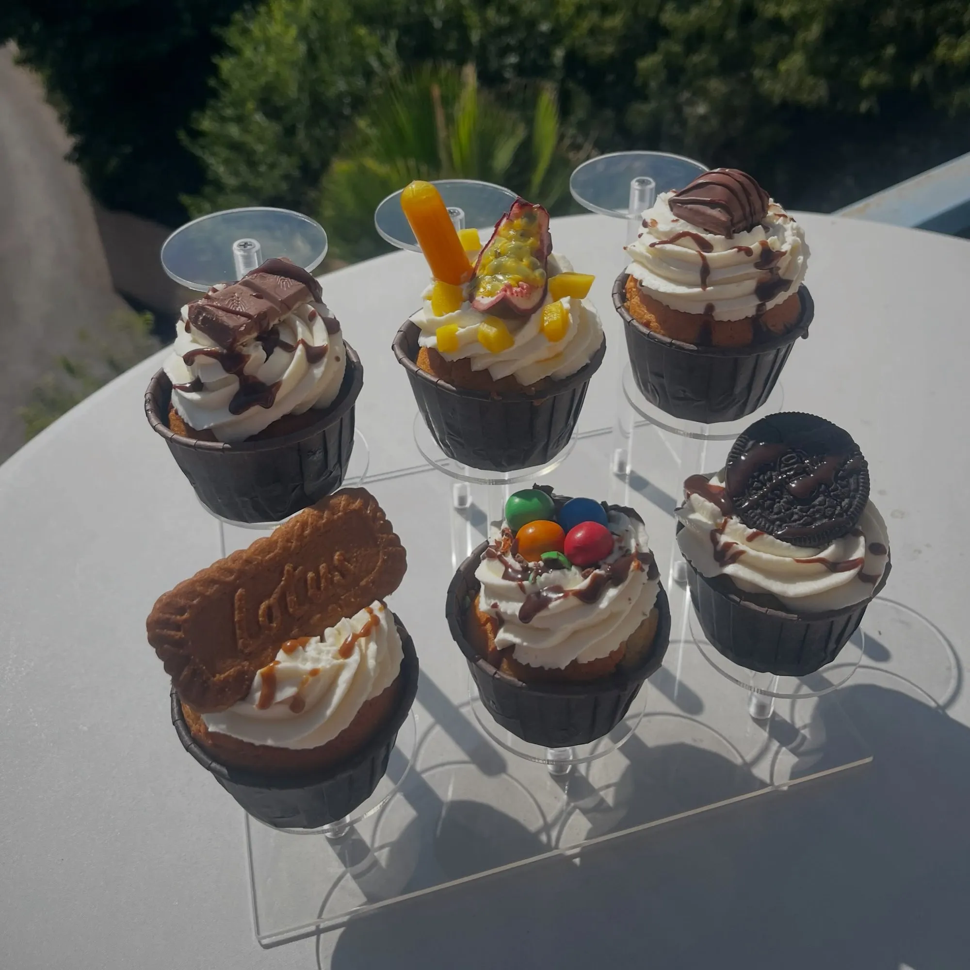 Cupcakes au chocolat décorés présentés sur un présentoir transparent