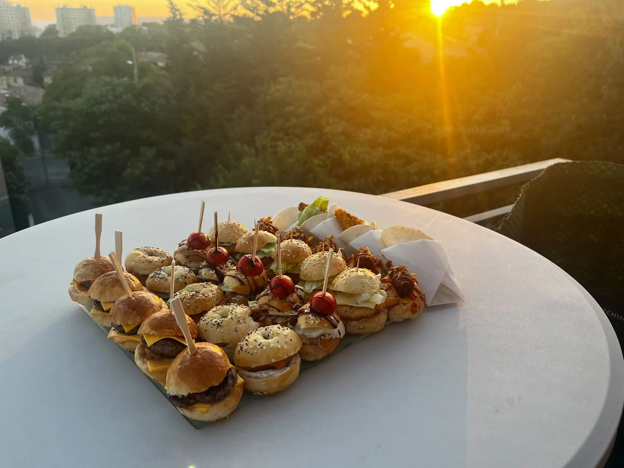 Plateau de mini-burgers, mini-bagels et wraps sous la lumière dorée du coucher de soleil